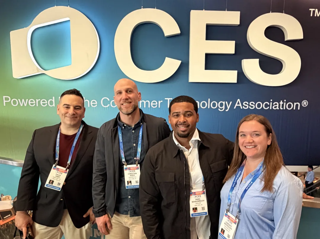 How cleantech brands stand out at CES-v2 Four attendees wearing CES badges pose in front of a large CES logo